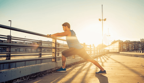 Man stretching outside against a cement wall.