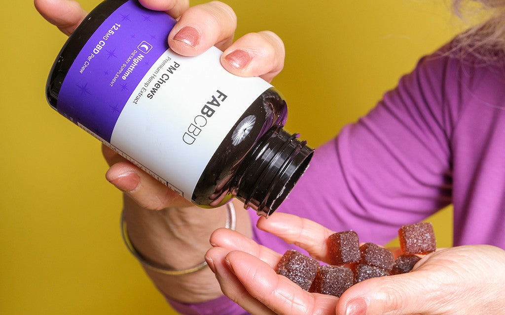 A woman pours CBD sleep gummies from the jar into her hand