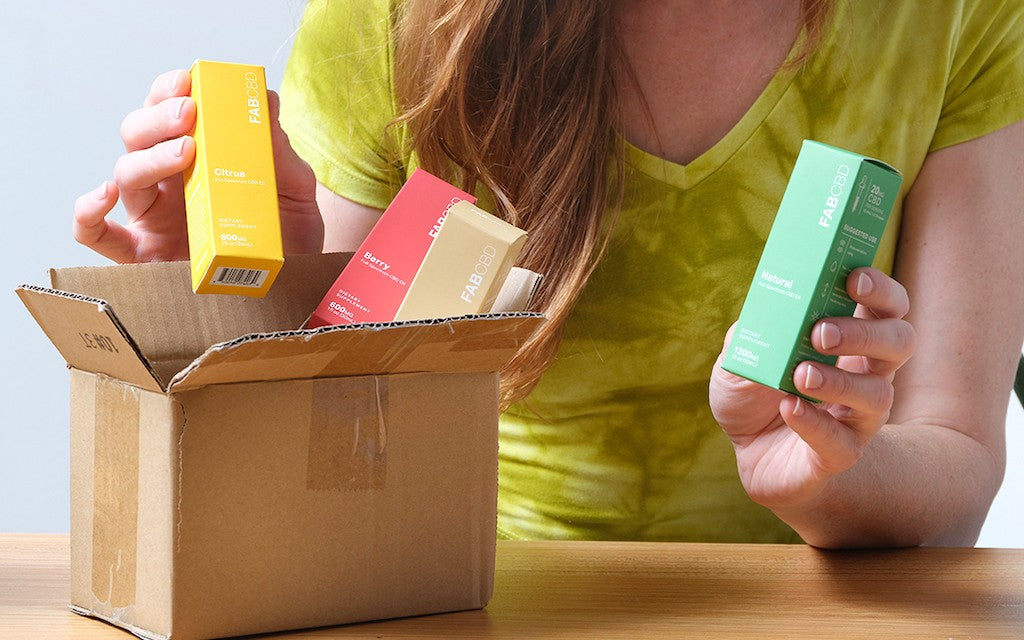 A woman opens a box of CBD products from the mail