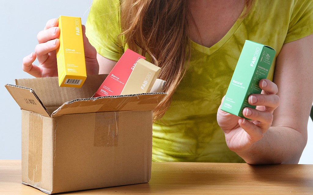 A girl opens a package containing colorful boxes of CBD oil