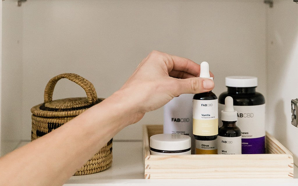 A hand reaching up to a shelf full of CBD products