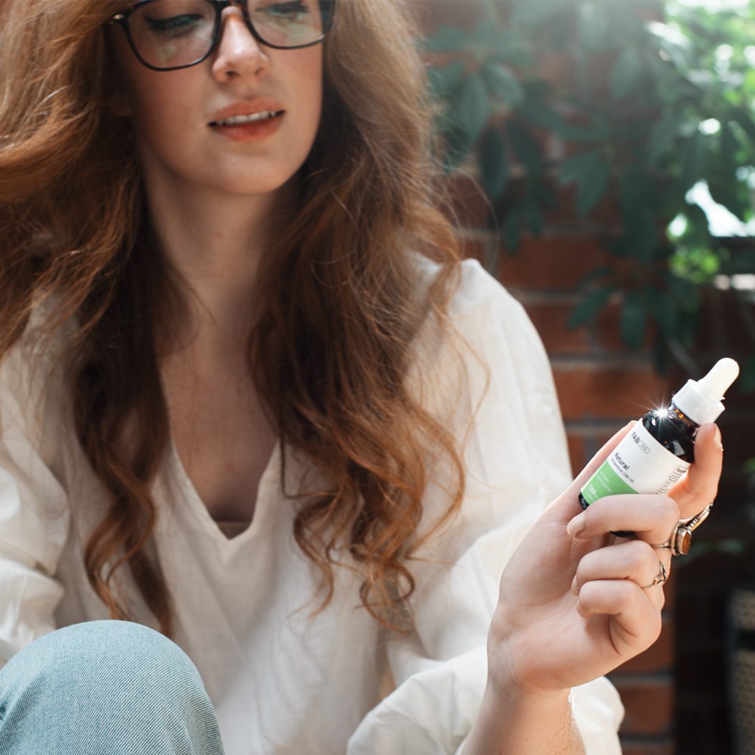 A young woman reads the label of a CBD oil bottle