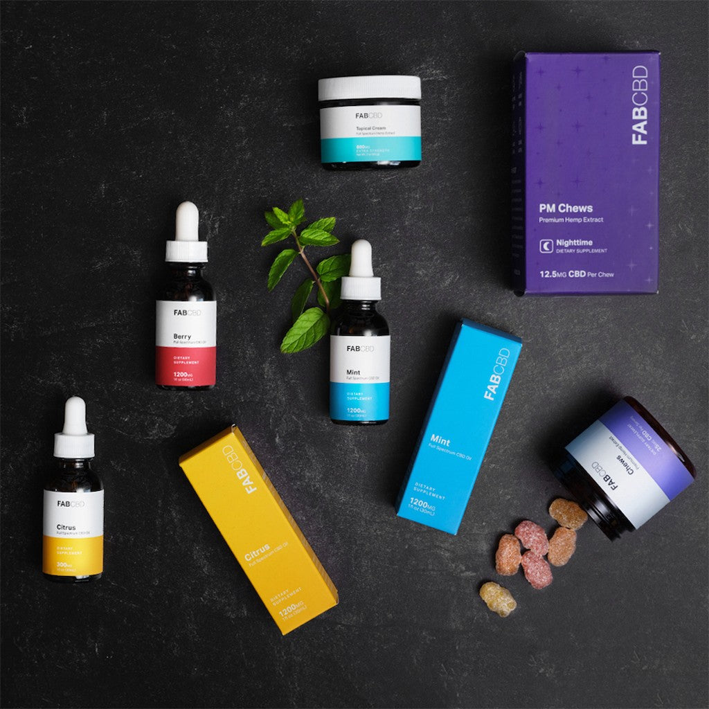 An array of FAB CBD products on a dark grey surface