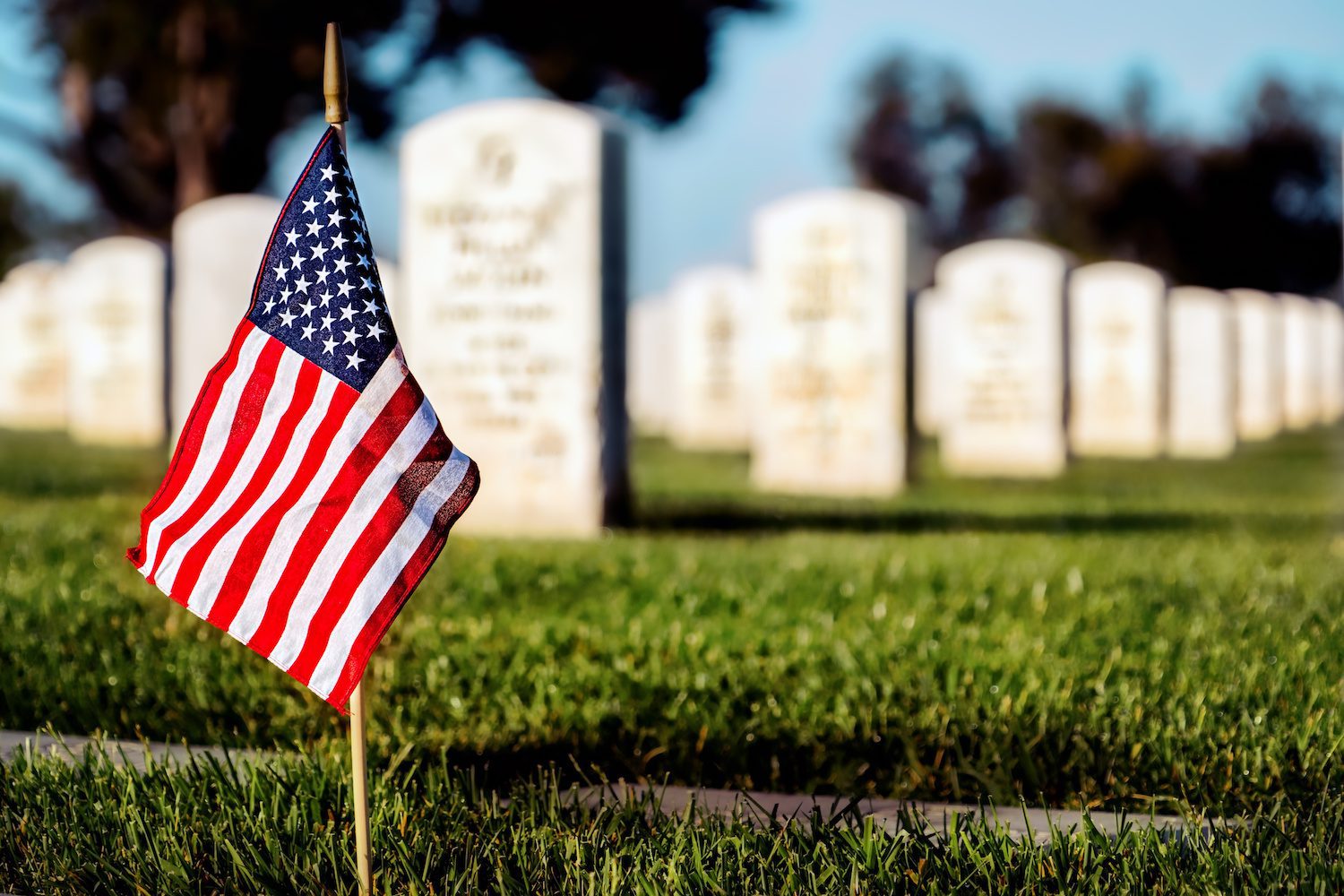 An American flag planted near headstones in a military cemetery