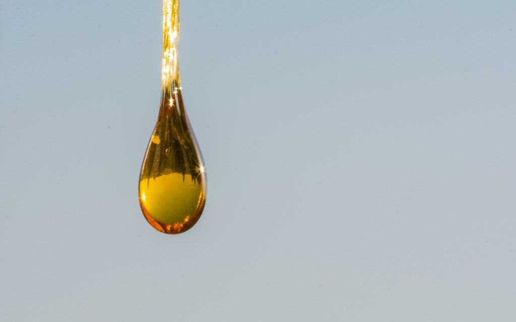 A close-up of a golden drop of CBD oil