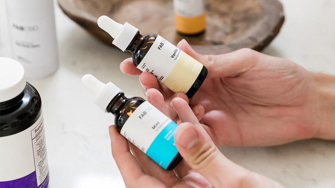 Somebody holding two full spectrum CBD oil bottles side-by-side for comparison