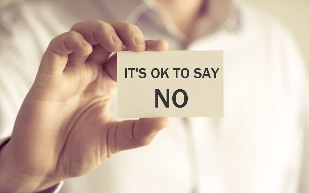 A person holds up a card that says "It's ok to say no"