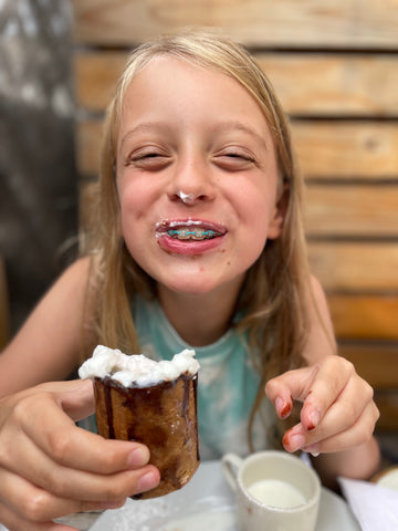 Smiling young girl holding a dessert in her hand and with whipped cream on her nose