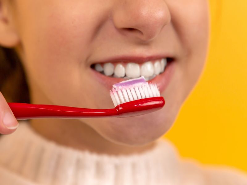 Woman brushing teeth with non-vegan toothpaste