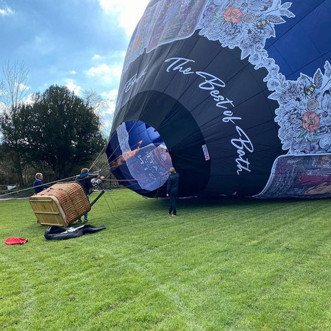 Bath gin hot air balloon inflating on the lawn at Haselbury Mill in Somerset before a yeovil balloon ride