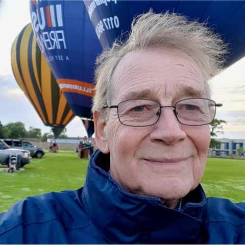 Selfie of a balloon pilot in front of lots of hot air balloons in Bristol.