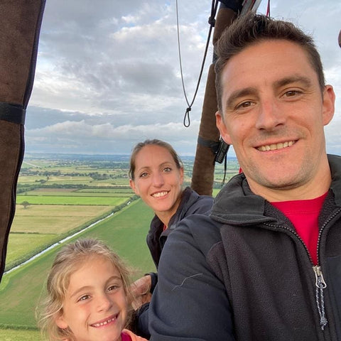 Family smiling in a hot air balloon with a view of the Somerset Levels.