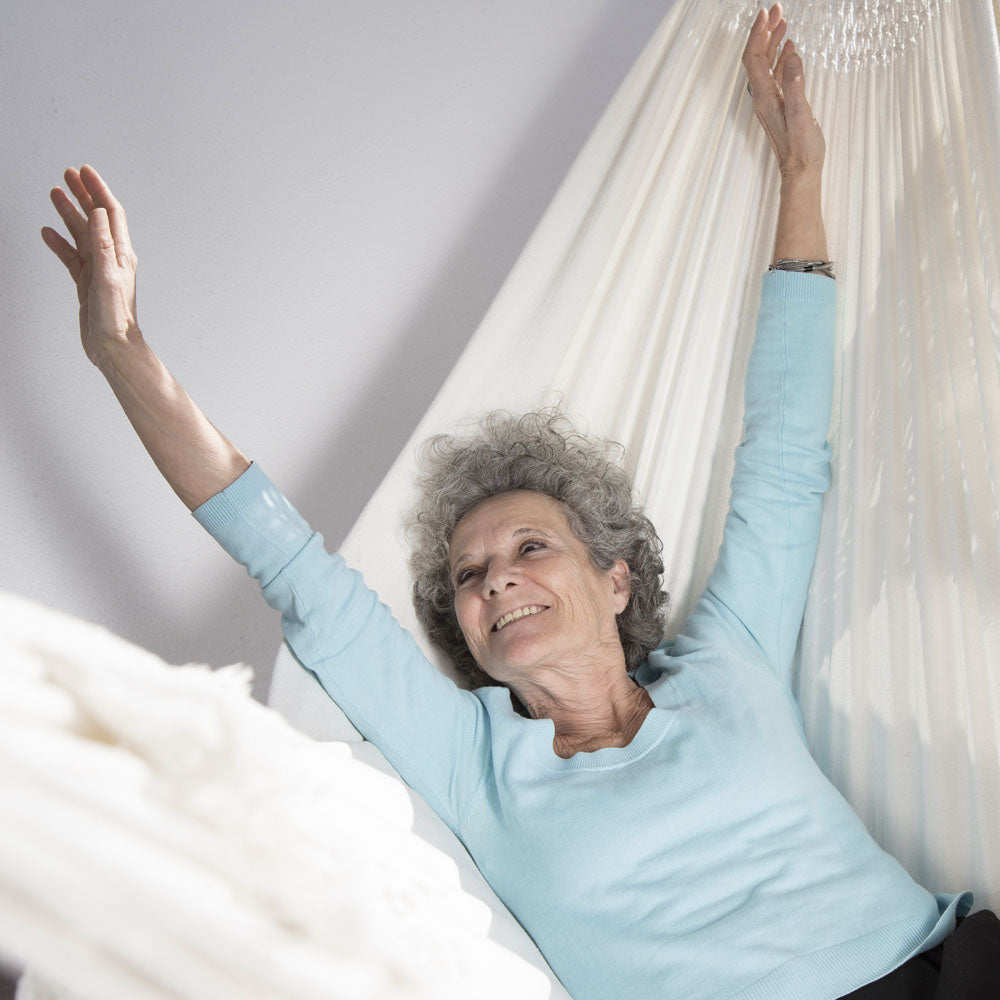 A senior woman lying in a white hammock