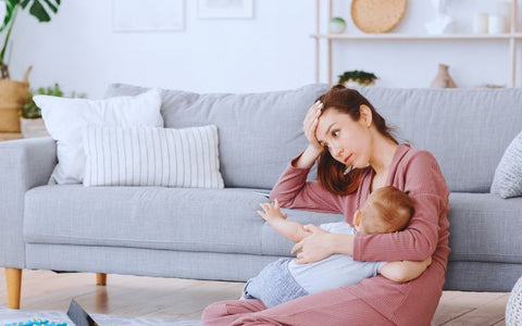 Fáradt anya babával a kézben a földön ül