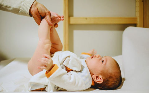 újszülött baba pelenkázásánál villás fogással fogják a baba lábát