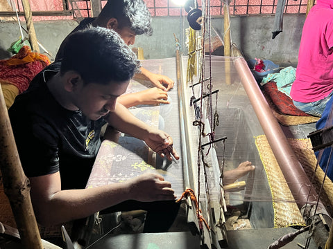 Two young weavers work together on an intricately designed Jamdani sarees