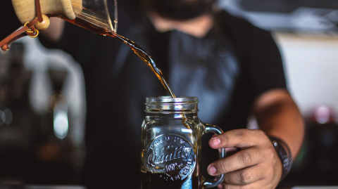 Barista pouring cold brew coffee into a glass bowl