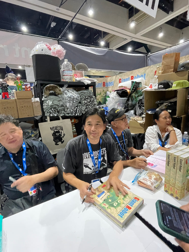 Luke Chueh, Martin Wong, Eric Nakamura, and Lynn Padilla sit and sign book at the Giant Robot 2024 Comic Con San Diego booth 1729.