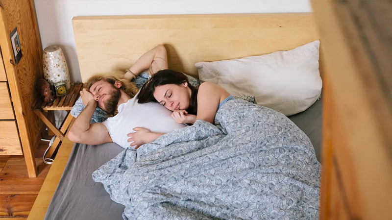 Middle aged couple laying on grey earthing sheet waking up after sleep feeling refreshed