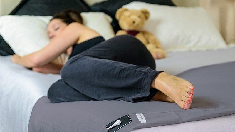 Woman sleeping on a comfortable bed that is grounded with earthing harmony half bed sheet