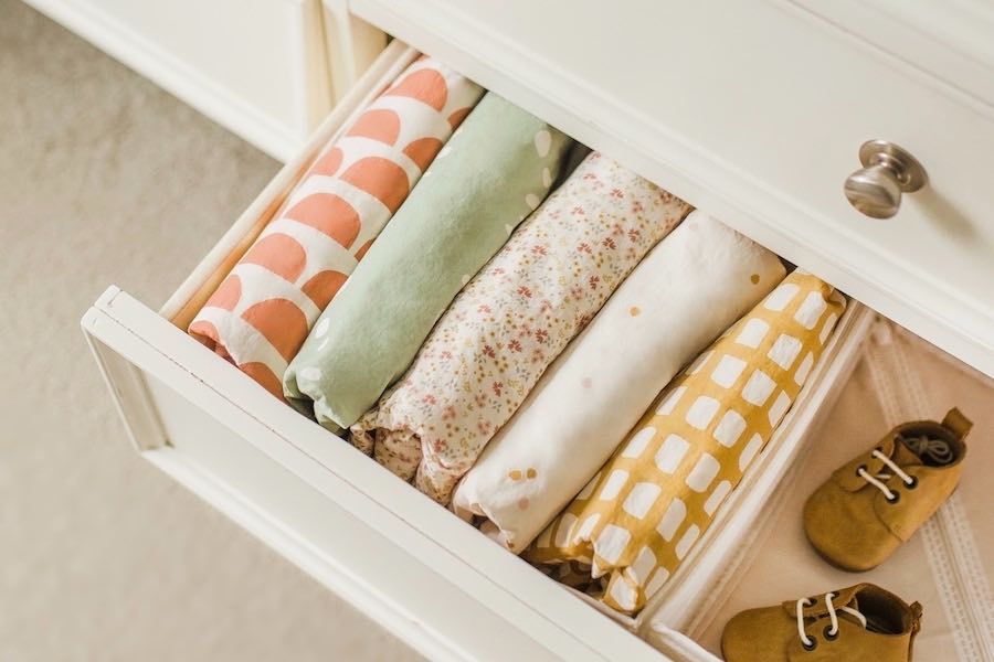 Oolie organic cotton crib sheets, displayed in an open dresser drawer, in five different prints.