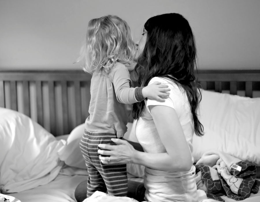 A young girl and her mom, together in the family bed.