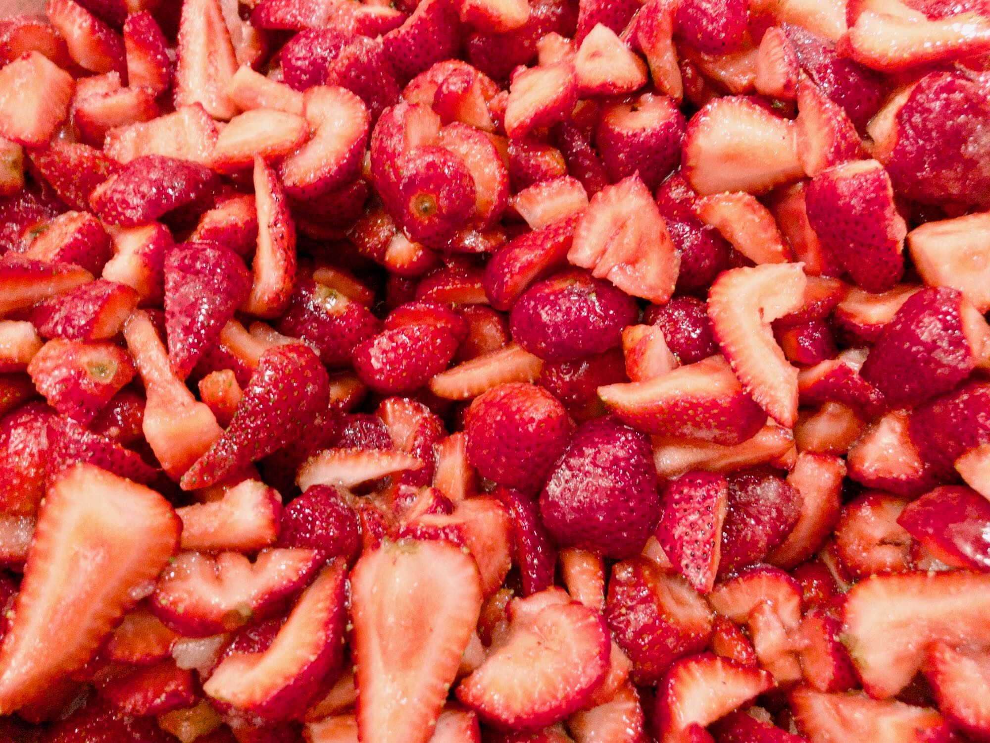 Close-up view of ripe, red strawberries, sliced and tossed with sugar.