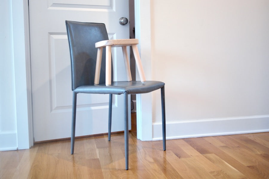 A stool balanced precariously on top of a chair, sitting in front of a door that is slightly ajar.