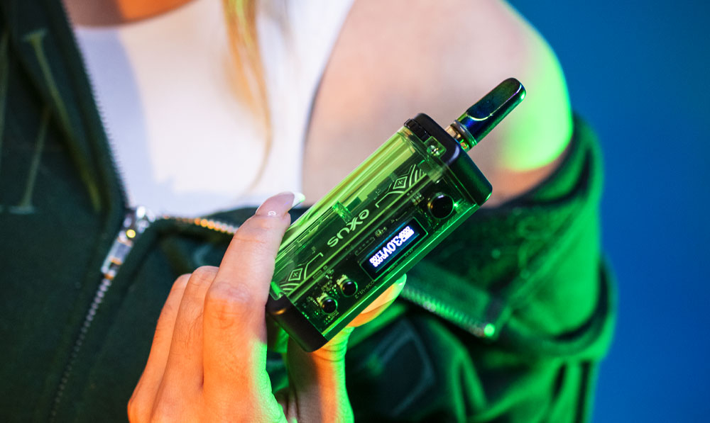 Woman holding Exxus Adapt in front of blue studio background under green lighting