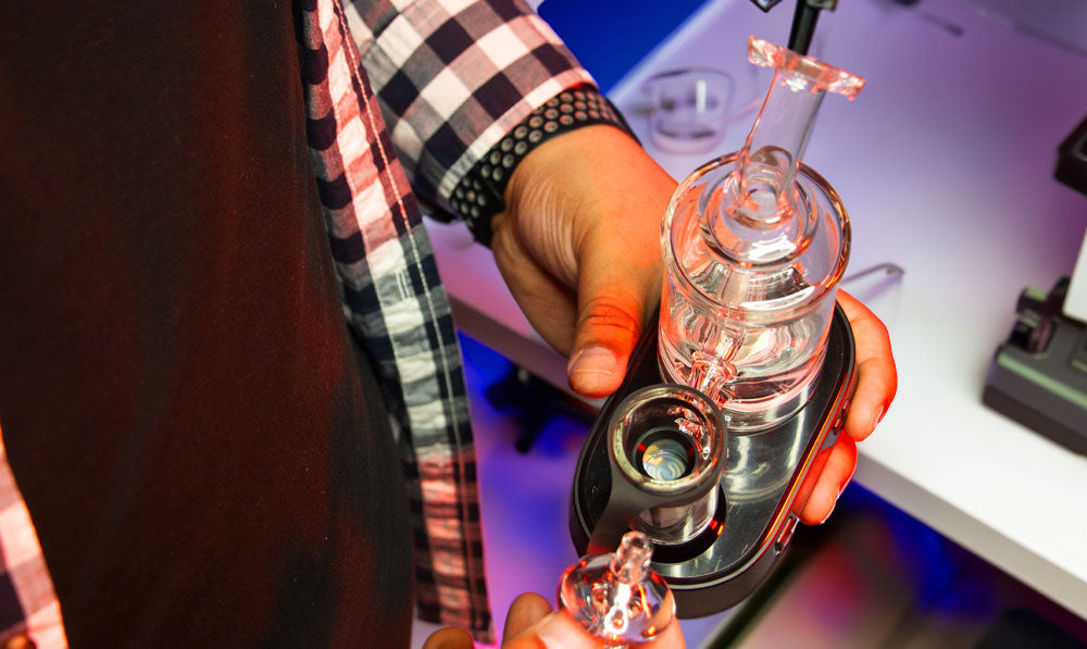 Man holding Exxus Go Plus with carb cap open over science table