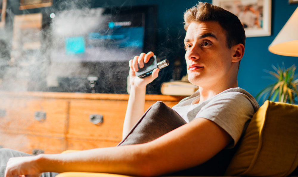 Man sitting in chair vaping comfortably at home