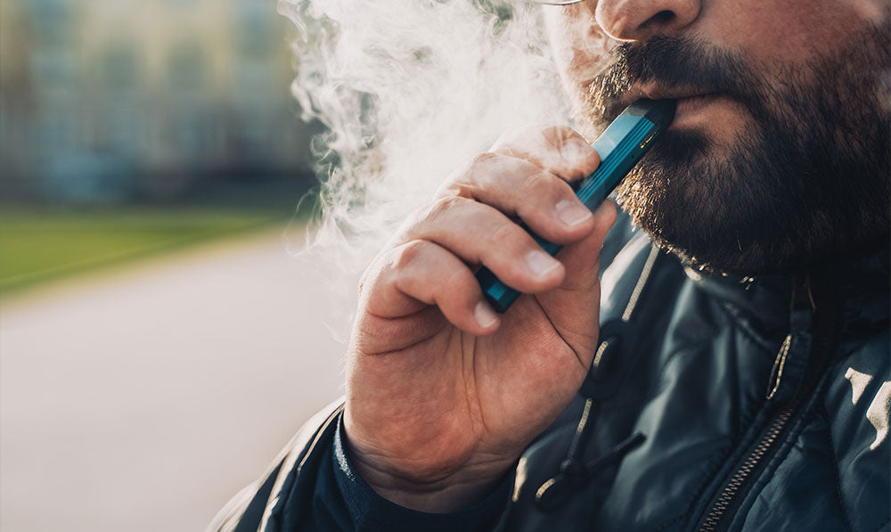 Man vaping mouth to lung vaporizer outside