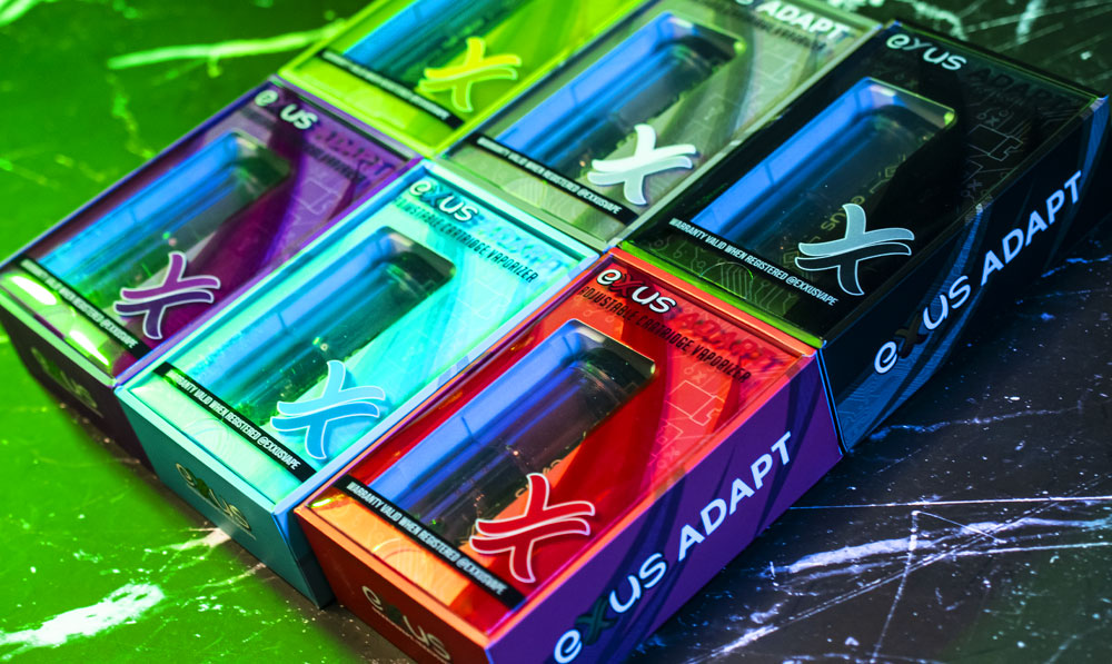 Exxus Adapt vaporizers in packaging resting on lightning themed display with green lighting