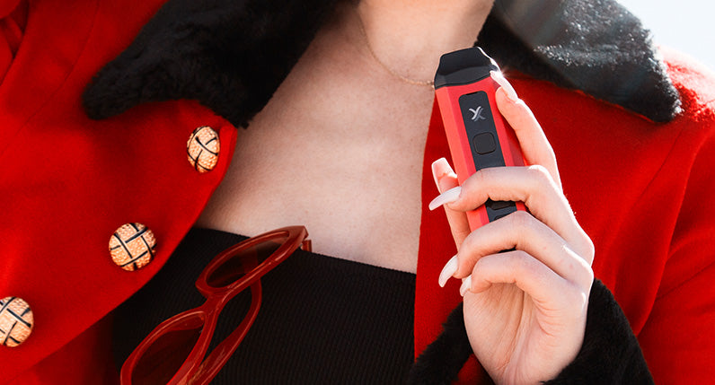 Woman with red glasses and jacket holds a red Exxus Mini Plus