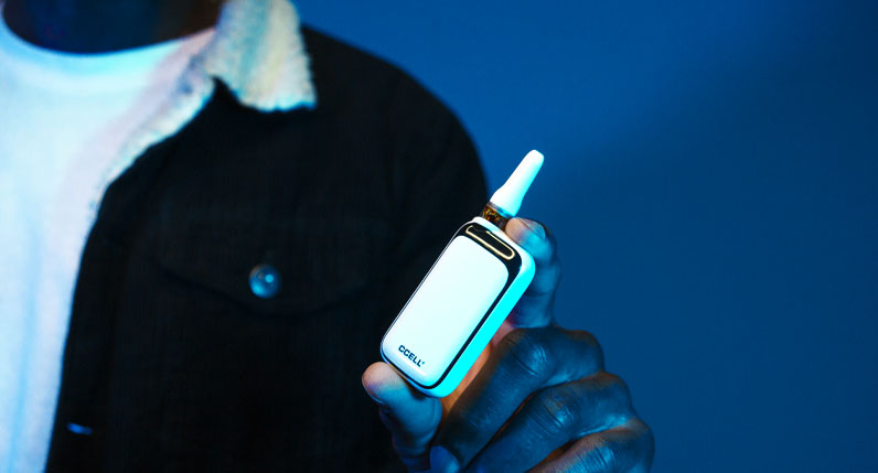 Man with black fuzzy coat holding the Exxus Rizo inside studio with dark blue background