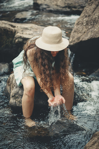 Woman holding water in hands in river 