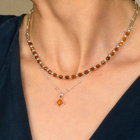 stacked necklaces worn on a neck with a carnelian and paperclip necklace and carnelian diamond shaped pendant