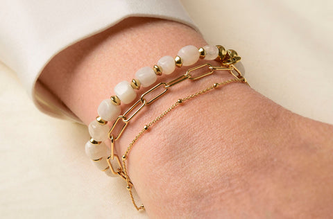 Wrist with a moonstone bracelet and stacks of bracelets