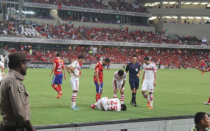 Zamalek player on the ground as his team mates & Al Ahly player watch on