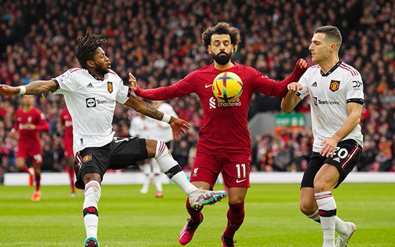 Mohammad Salah tries to control the football two United players