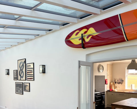Surfboard adding interest to gallery wall in a beach house in cornwall