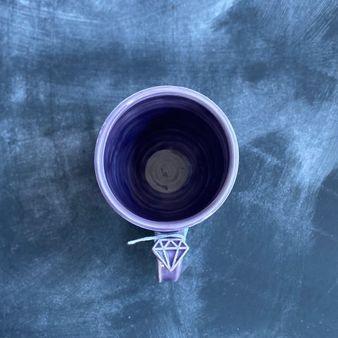 purple mug from above, showing diamond thumbhold detail where the celadon glaze has pooled a deeper purple