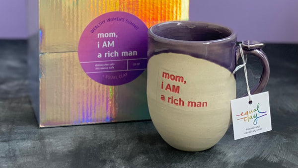 purple mug beside holographic gift box with "mom i AM a rich man" label