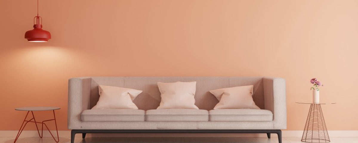 parede de sala pintada em tons laranja e decoração com sofá e candeeiro