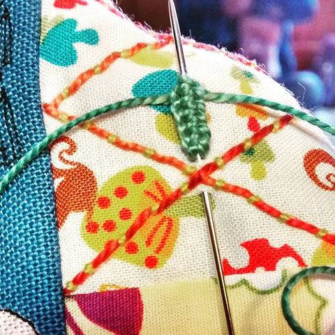 A close up of decorative green, red and yellow hand stitching