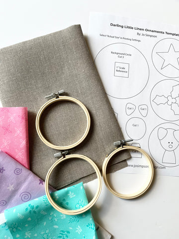Ornament supplies, flax colored linen, pastel scraps, 3” embroidery hoops, and templates.