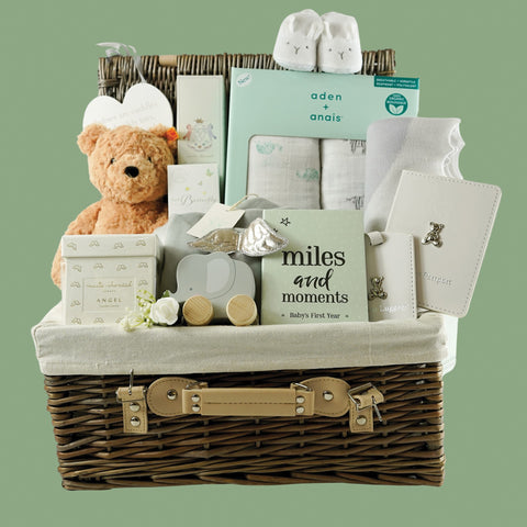 Luxury baby hamper basket with luxury marie chantal candle, aden and anais muslin swaddles, babys first Steiff teddy, Marie Chantal angels wings grey velour sleepsuit, Marie Chantal hairbrush, Baby's first passport set in white with silver plated elephant and matching luggage lable