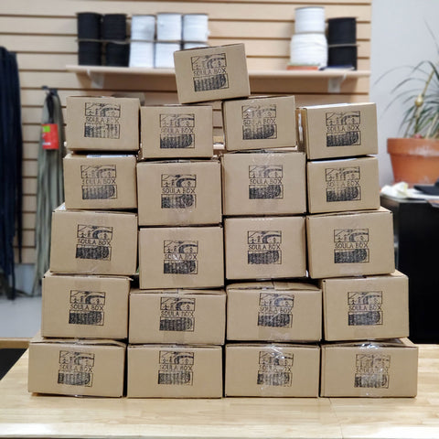A pile of Soula Boxes. These gift boxes were packed with items from eleven different women owned businesses and gifted to local healthcare workers.