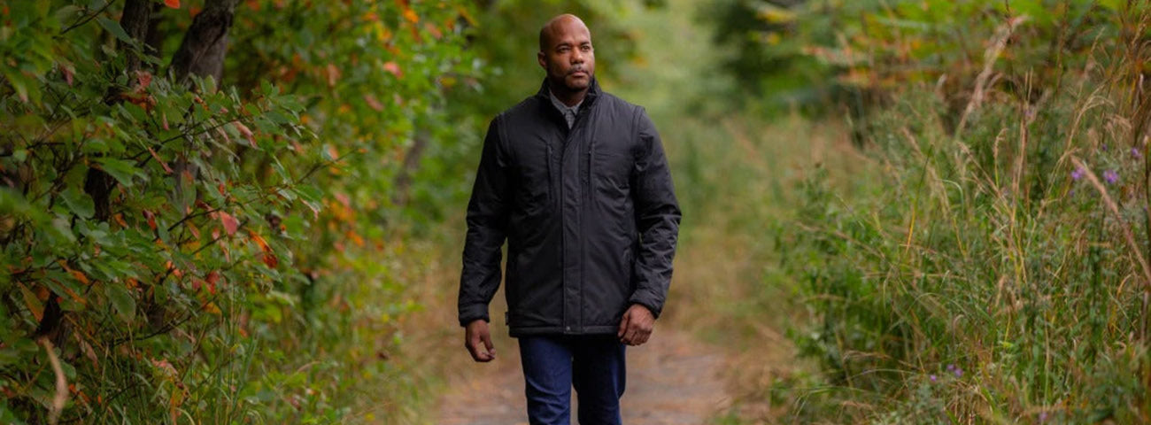 Man wearing SCOTTeVEST Revolution 2.0 photographer’s jacket in black with pocket diagram overlay.