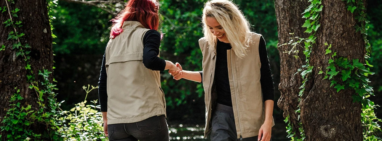 A woman wearing a SCOTTeVEST photography jacket in beige with pocket diagram overlay.